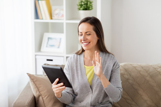 happy woman having video chat on tablet pc at home