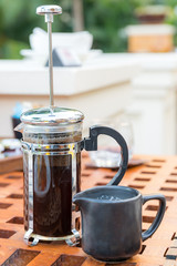 drinks, energetic, morning and caffeine concept - cup of black coffee and french press on table at...