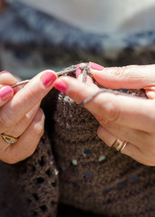 Senior woman crocheting a brown blanket relaxing in garden