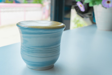 Big coffee creamy in blue mug on the desk. Concept coffee lover background.