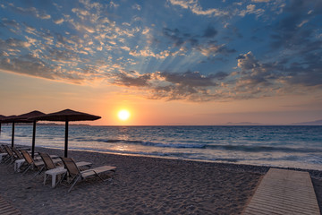 Beautiful sunset contre-jour on the sea shore, in a beach resort, with comfortable sunbeds and umbrellas