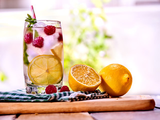 Cold water with lemon and mint leaf. Fresh raspberries lemonade with lemon slice and ice cubes. Non...