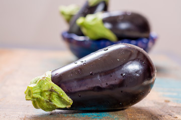 Ripe raw purple eggplants on a wooden background