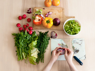The girl sits in the kitchen and preparing a salad, cutting bow. Flat lay. - 162266919