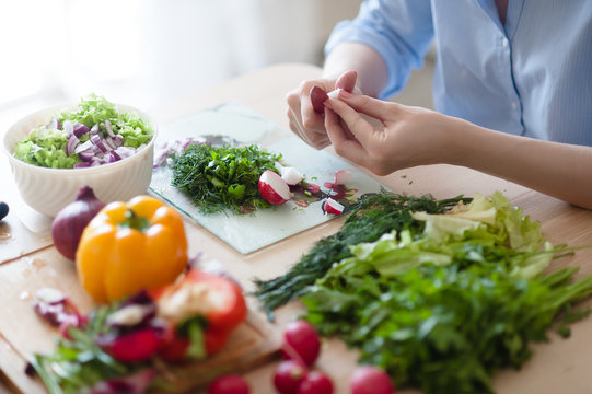 The girl is a vegetarian sitting in the kitchen and prepares a vegetable salad