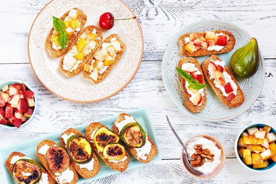 Italian Crostini With Ricotta, Cut Fresh Fruits (cherry, Pear, Peach) And Grilled Figs On Wooden Table. Top View Of Healthy Summer Snack.