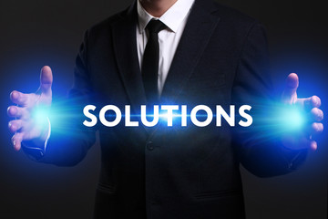 Business, Technology, Internet and network concept. Young businessman working on a virtual screen of the future and sees the inscription: Solutions