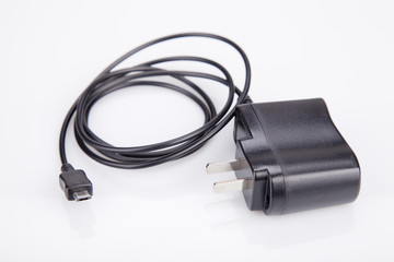 Black cell phone charger cord on a white surface. Cell phone charger isolated on white background.