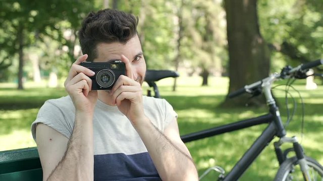 Handsome man doing photos on old camera in the park and enjoying this, steadycam shot
