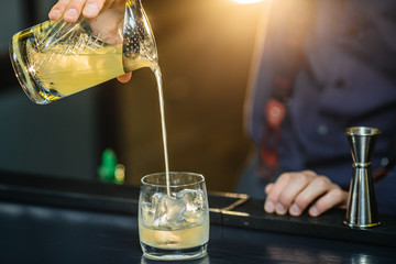Bartender is making cocktail at bar.