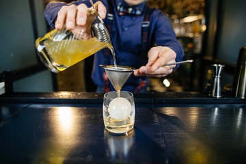 Bartender is making cocktail at bar.