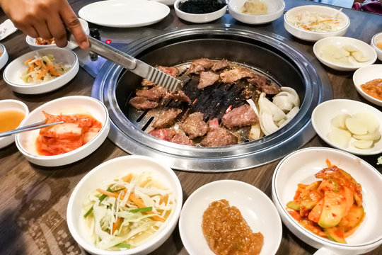 Person barbecue beef on bbq pit during korean meal set