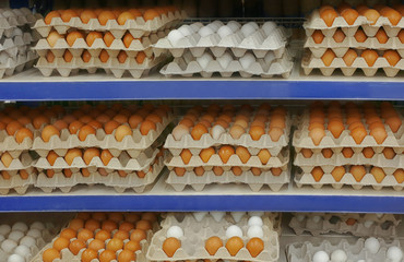Cardboard trays with chicken eggs on shelves at supermarket