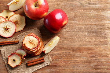 Composition with tasty apple chips and cinnamon on wooden table