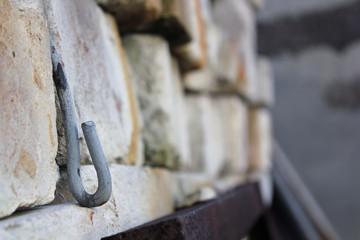 Metal aluminum hook on the wall of bricks with rust marks