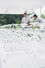 Glasses on reserved table. Waiters are serving banquet table