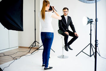 Female photographer taking picture of a male model in studio - 162273523