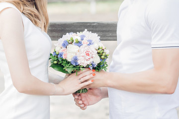 Obraz na płótnie Canvas hands of bride and groom hold beautiful wedding bouquet