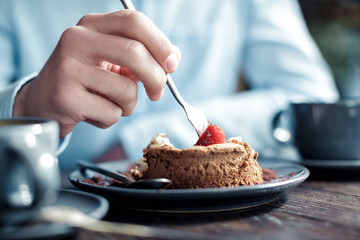 Man eating cake with strawberries in cafe, close-up