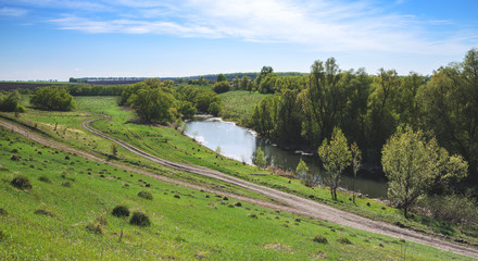 Fototapeta na wymiar Sunny spring landscape with river and ground road