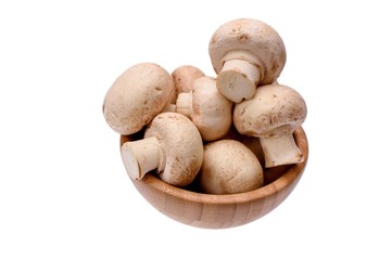 White mushrooms champignons lie in a wooden cup, isolated on a white background