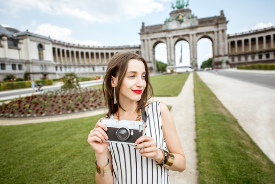 Young female traveler standing with photo camera on the famous Triumphal arch background in Brussels