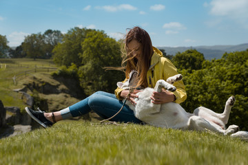 Junge Frau und schöner labrador retriever hund welpe sitzen nebeneinander auf einem sonnigen Hügel und kuscheln