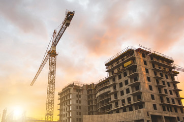 Fototapeta premium Building crane at sunset and building an orange sky.