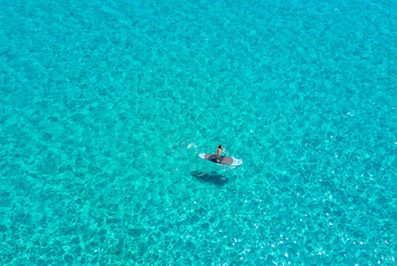 Frau auf einem Stand Up Paddle Board auf smaragdgrünem Wasser der Ägäis