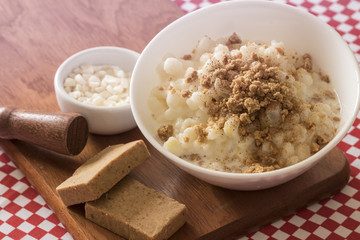 Brazilian dessert sweet canjica of white corn with pacoca sweet in bowl and towel. Festa Junina Party Brazilian Culture Concept Image.