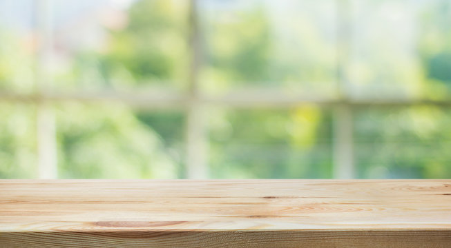 Wood table top on blur of window glass and abstract green from garden backgrounds