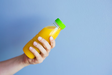 Close-up of female hand holding a bottle with juice