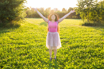 Naklejka na ściany i meble Free happy young woman raising arms watching the sun in the background at sunrise
