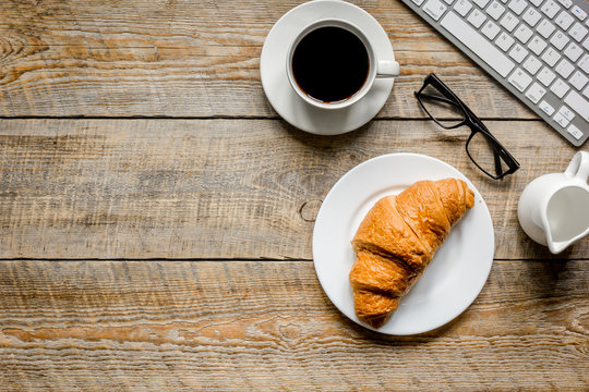 coffee and croissant for breakfast of businessman wooden office desk background top view space for text