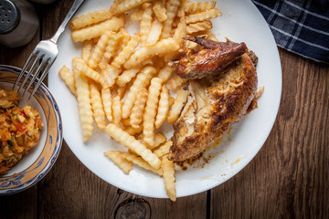 Roasted chicken with french fries on a plate.