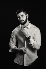 Young handsome muscular man with a beard, posing on a black background