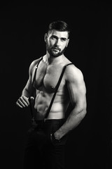 Naklejka premium Young handsome muscular man with a beard, posing on a black background