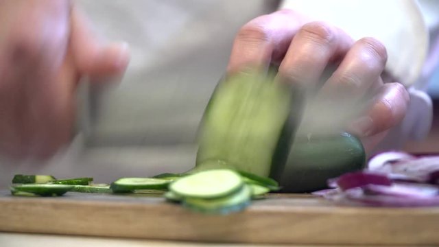 Closeup of the chef cutting cucumber on the wooden bord