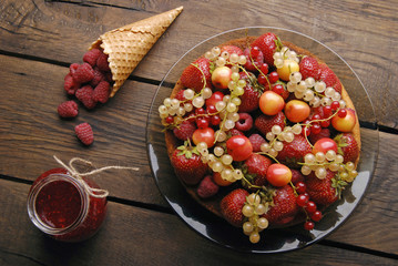 Sponge cake with different summer fruits and raspberries on wood table