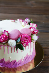 Obraz na płótnie Canvas White cake with a rose decoration on a wooden background