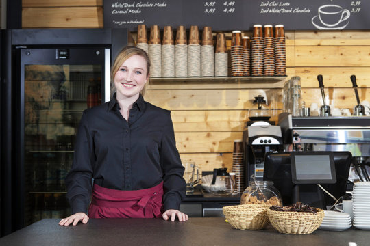 Shop assistant standing behind counter in coffee shop