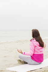 Fototapeta na wymiar woman practices yoga and meditates in the lotus position on the beach