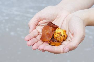 Amber in the hand with a bright reflection on the palm against the background of the sea.