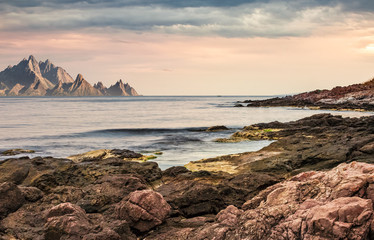 seascape with rocky coast and mountain ridge with high peaks