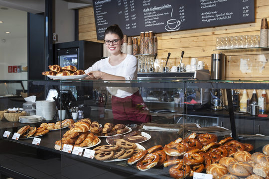Waitress in coffee shop arranging croissants on counter