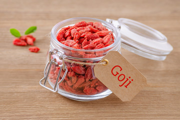 goji berries in a glass jar on wooden background