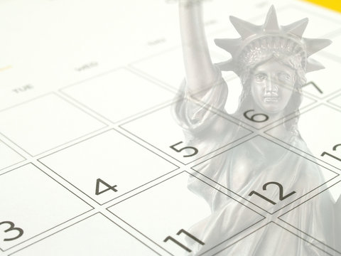 double exposure of bronze metallic statue of liberty national monument on grid of dates in July 2017 of desk calendar page, independence day or american national day concept, selective focus at 4th