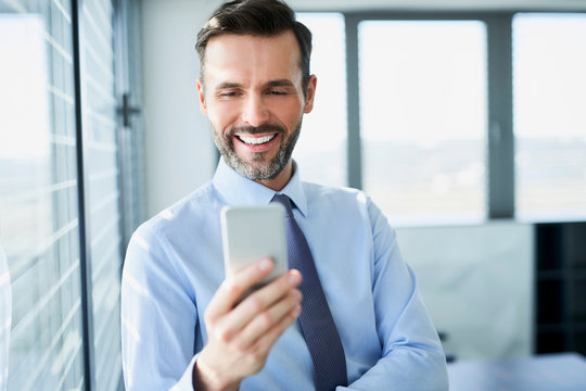 Happy man using phone to work while in office
