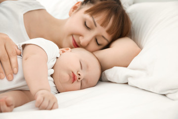Fototapeta na wymiar Young woman with cute sleeping baby lying on bed at home