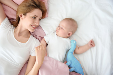 Fototapeta na wymiar Young woman with cute sleeping baby lying on bed at home